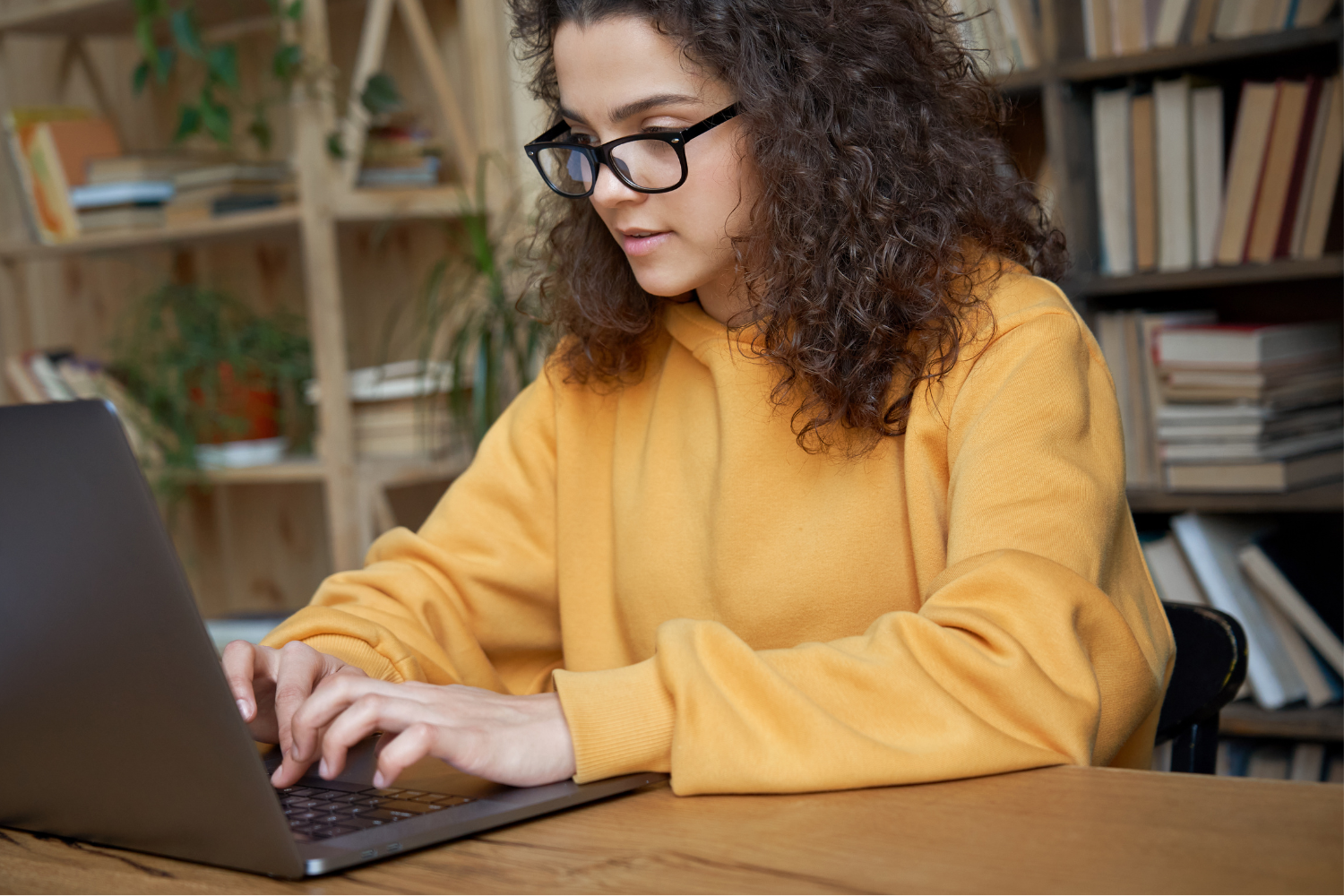 Teenager in a yellow top using a laptop