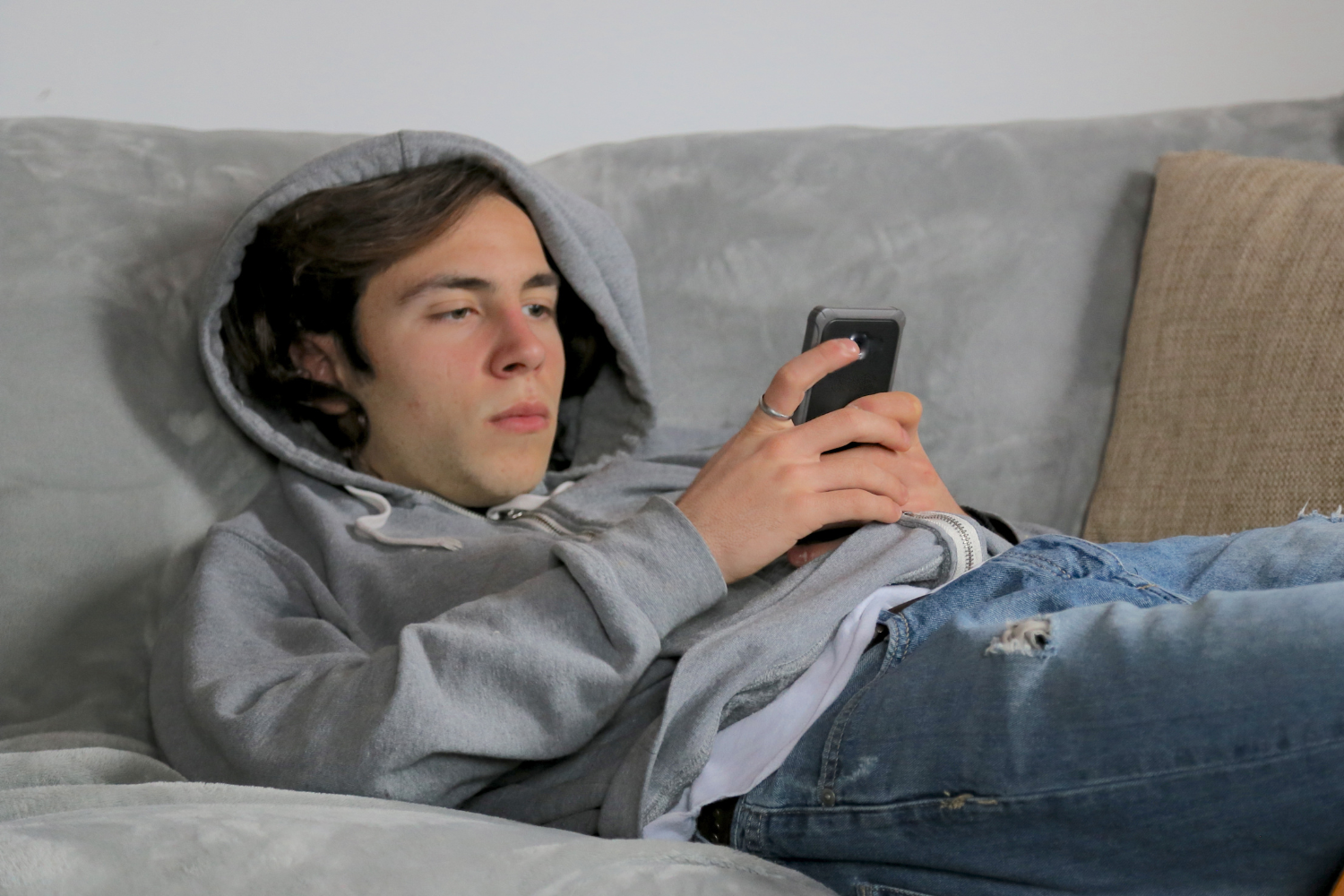 Teenage boy laid in bed looking at a smart phone