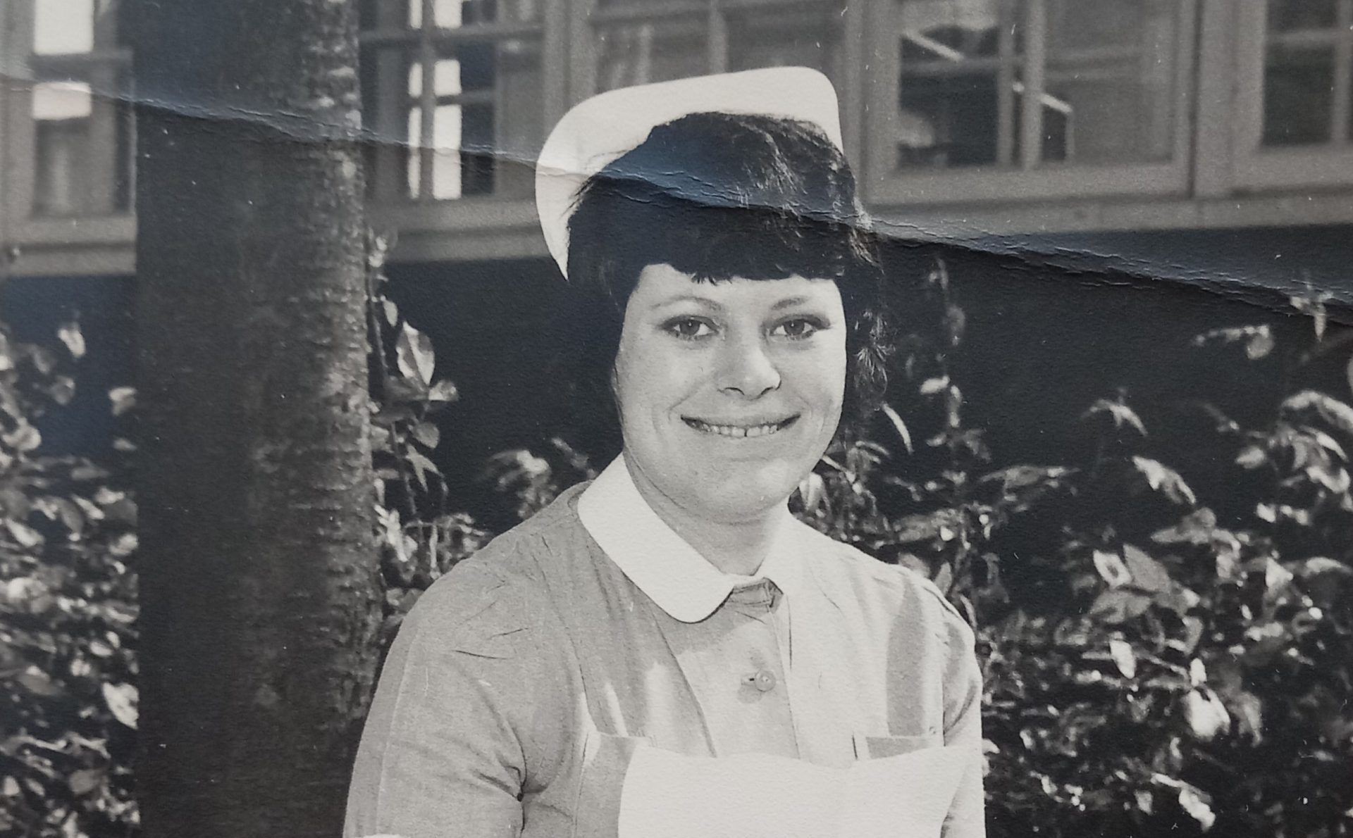 An old black and white photo of Patricia a nurse sat outside in nursing uniform
